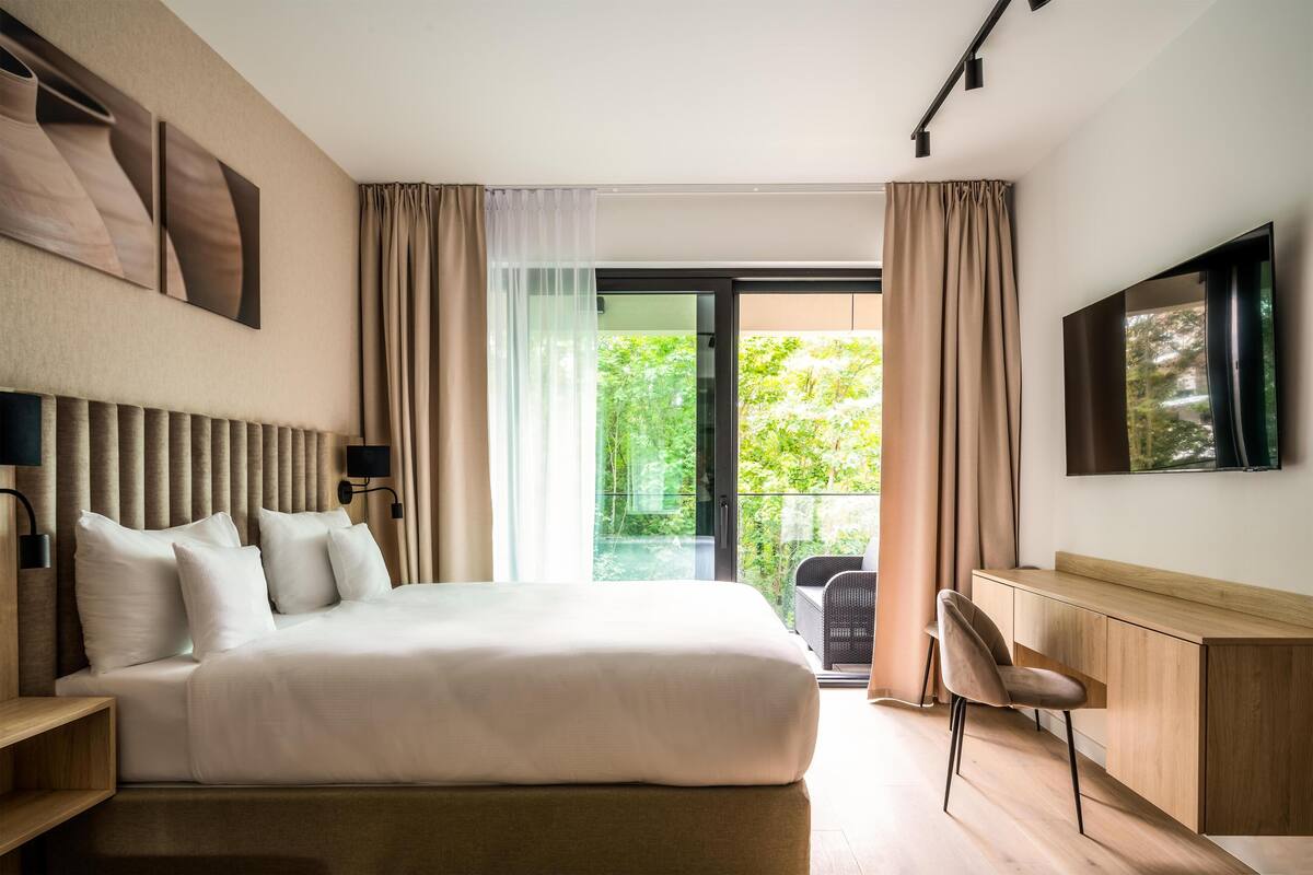 Une chambre d’hôtel moderne avec un grand lit, un bureau et une télévision.