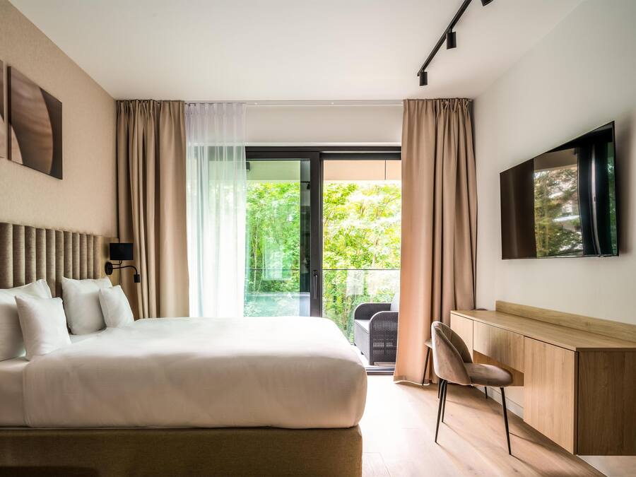 Ett modernt hotellrum med en stor säng, ett skrivbord och en TV.