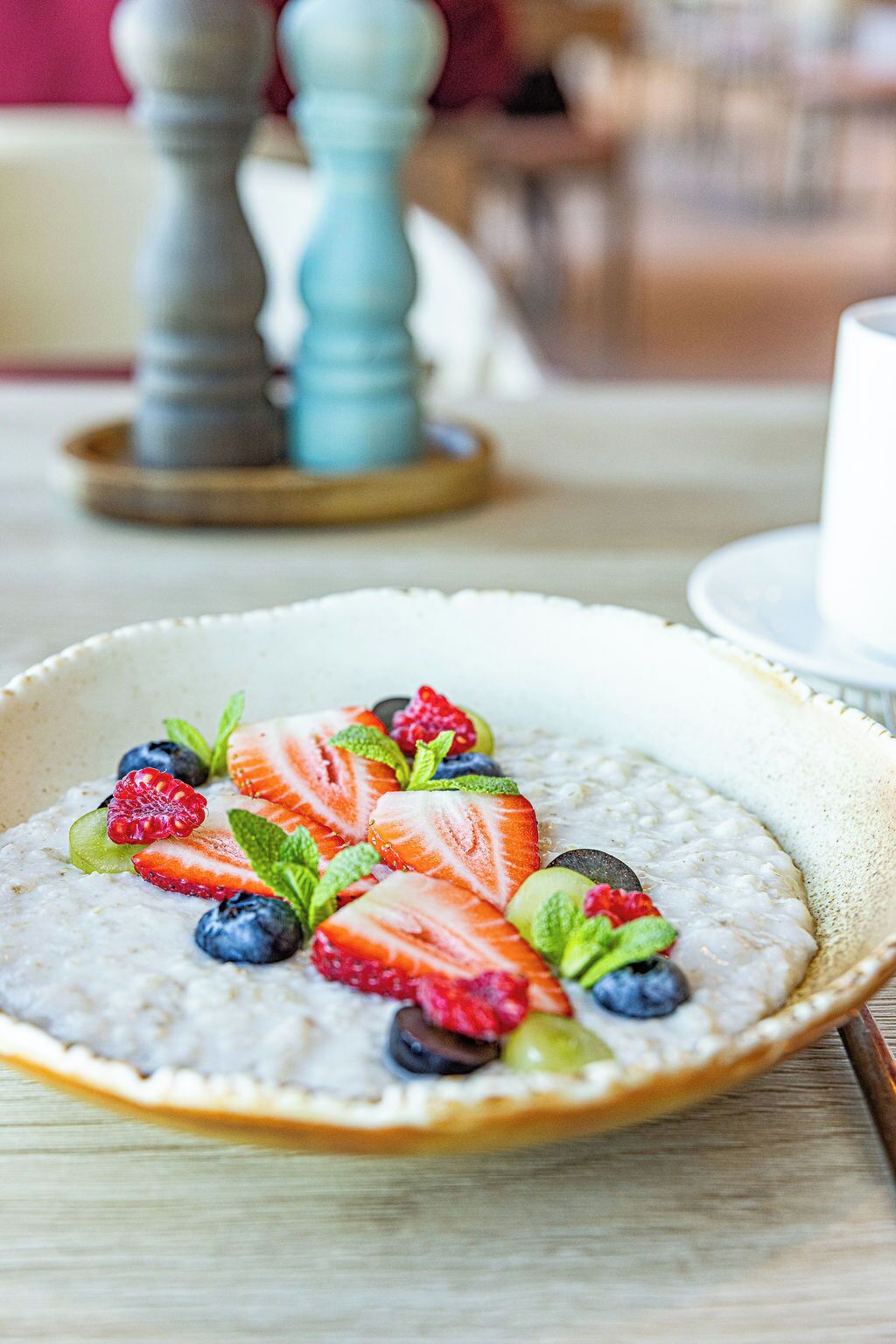 Un tazón de avena con fresas, arándanos y frambuesas sobre una mesa de madera.