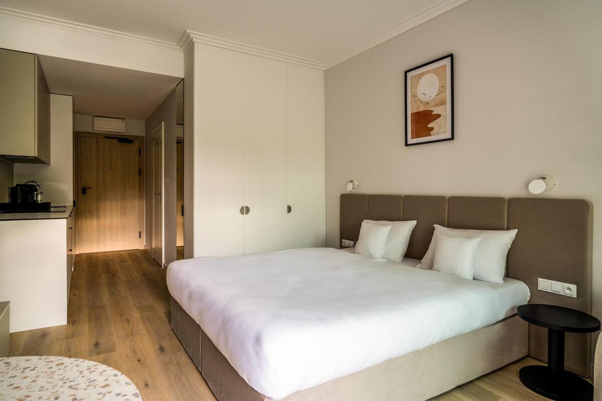 Une chambre à coucher moderne avec un grand lit, une table de chevet et une petite table ronde.