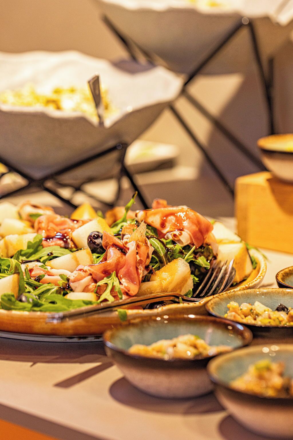 Una mesa con diversos platos, incluyendo una ensalada con vegetales y queso, y un plato con una rebanada de pan.