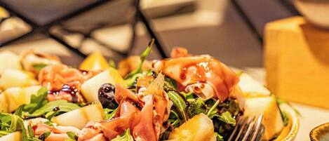 Una mesa con diversos platos, incluyendo una ensalada con vegetales y queso, y un plato con una rebanada de pan.