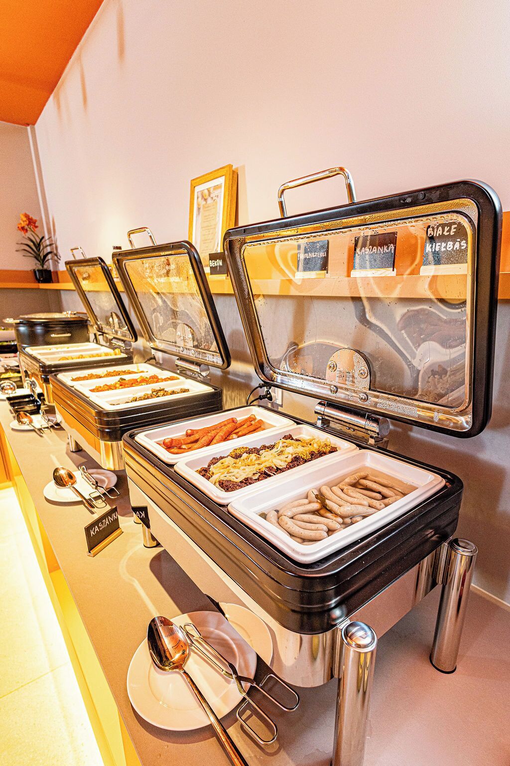 A buffet with labeled containers for various food items.