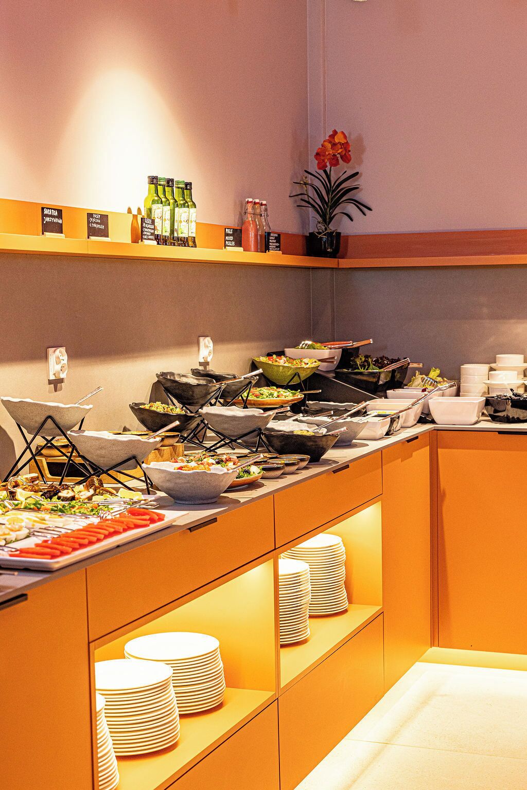 A buffet setup with various food items, condiments, and a potted plant.