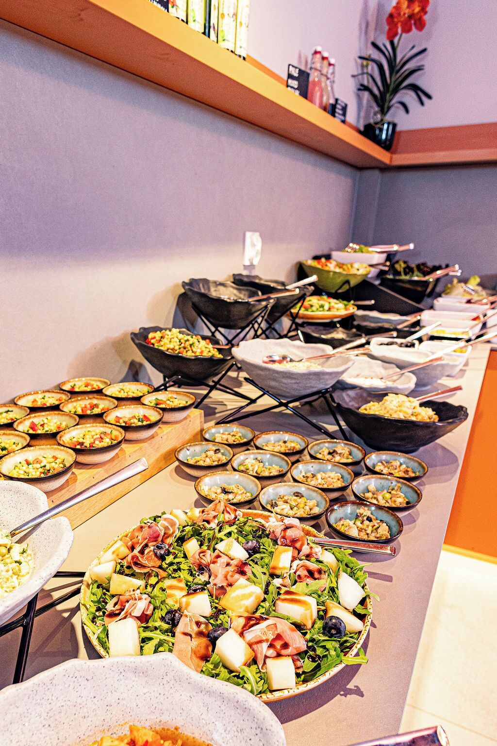 A buffet with various dishes, including salads and pasta, arranged on a long table.
