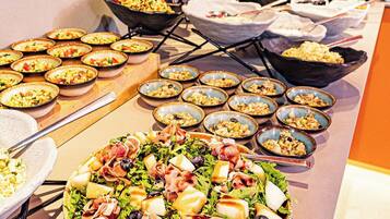 A buffet with various dishes, including salads and pasta, arranged on a long table.