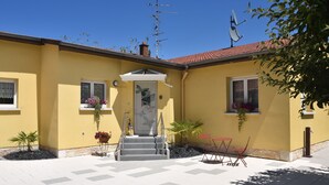 A yellow building with a tiled entrance, a satellite dish, and potted plants. - Pavilion well located for visiting the region (Ruelisheim)