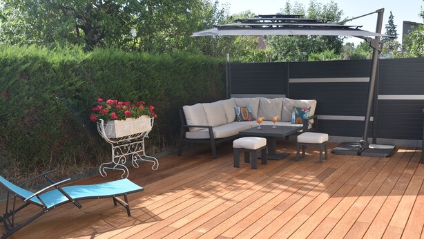 A wooden deck with a sofa, two chairs, a table, and a small garden bed with flowers. - Pavilion well located for visiting the region (Ruelisheim)