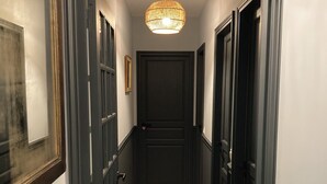 Un couloir étroit aux murs sombres et au plancher en bois, qui mène à une porte au fond.