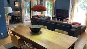 Un salon comprenant un canapé, un téléviseur, une table à manger et des chaises.