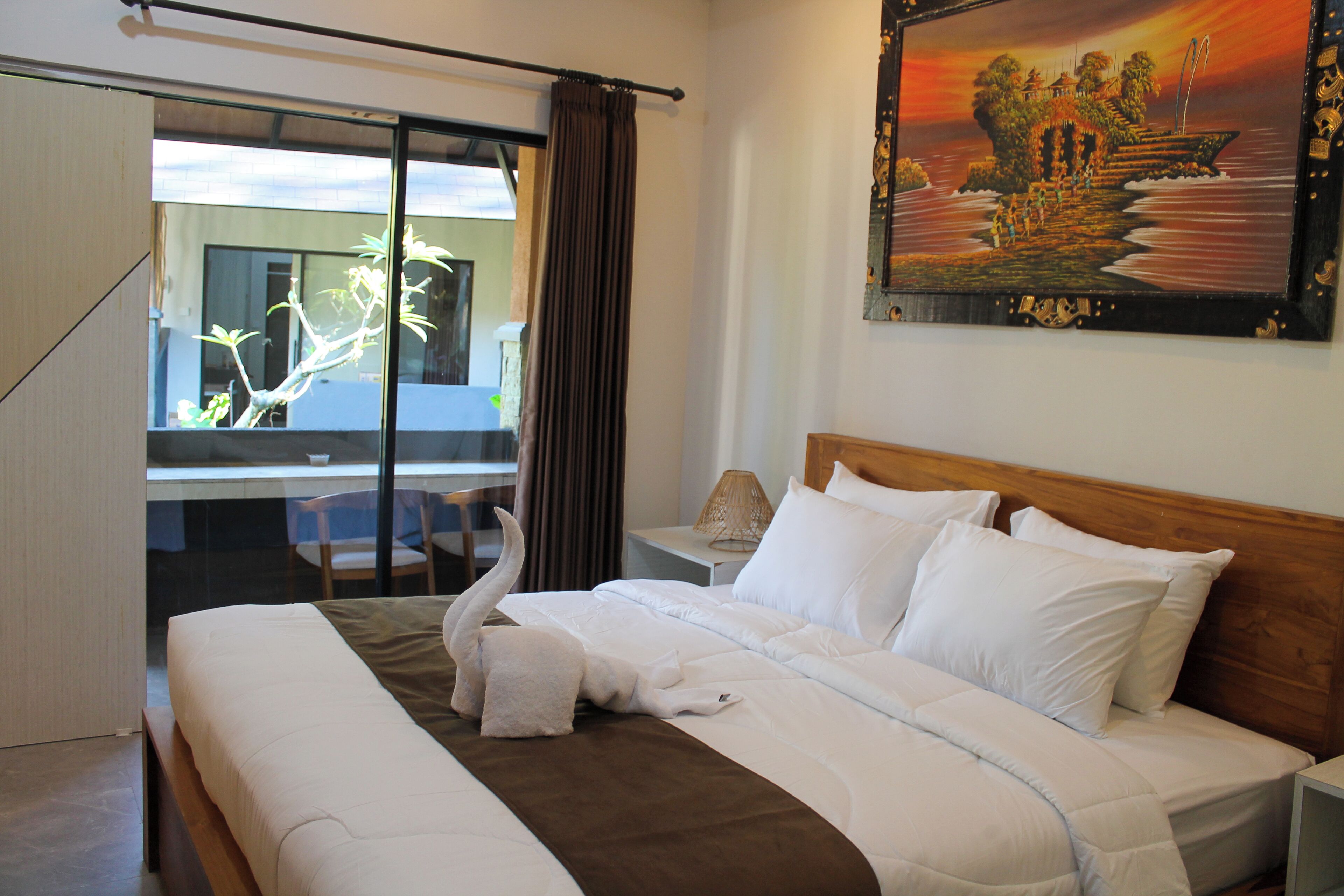 A hotel room with a large bed, a desk, and a view of a building through a glass door.
