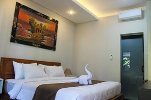 Une chambre d’hôtel avec un lit, un tableau au mur et une porte dotée d’un panneau en verre dépoli.