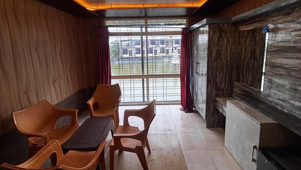 A room with a wooden ceiling, a large window with curtains, a dining table with chairs, and a counter.