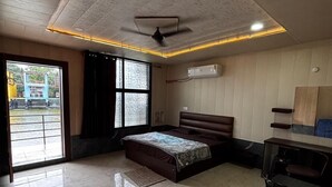 A modern bedroom with a bed, a desk, and a ceiling fan.