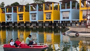 A boat with passengers on a calm water body, surrounded by colorful buildings with multiple levels and windows.
