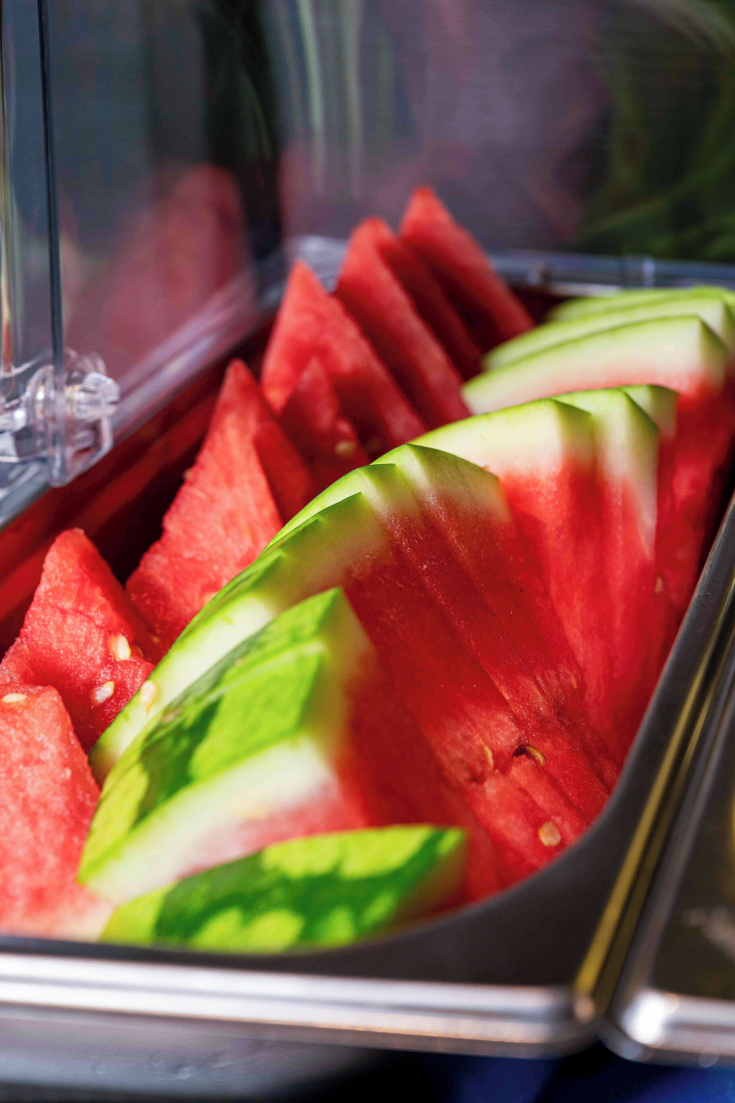 A clear view of a food display with sliced watermelon and cucumber.