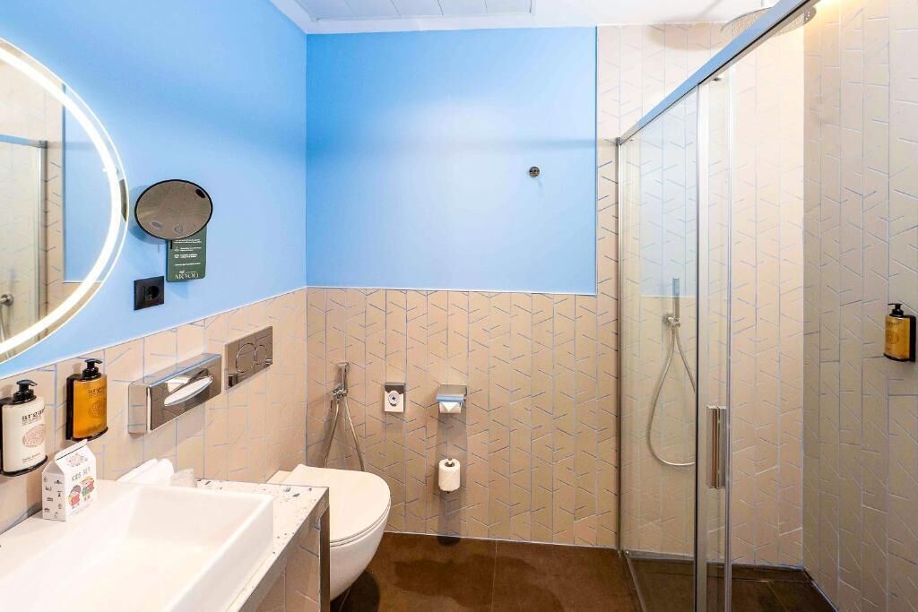 A modern bathroom with a blue accent wall, a glass shower enclosure, and a white sink with a mirror.
