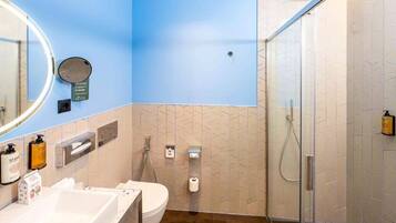 A modern bathroom with a blue accent wall, a glass shower enclosure, and a white sink with a mirror.