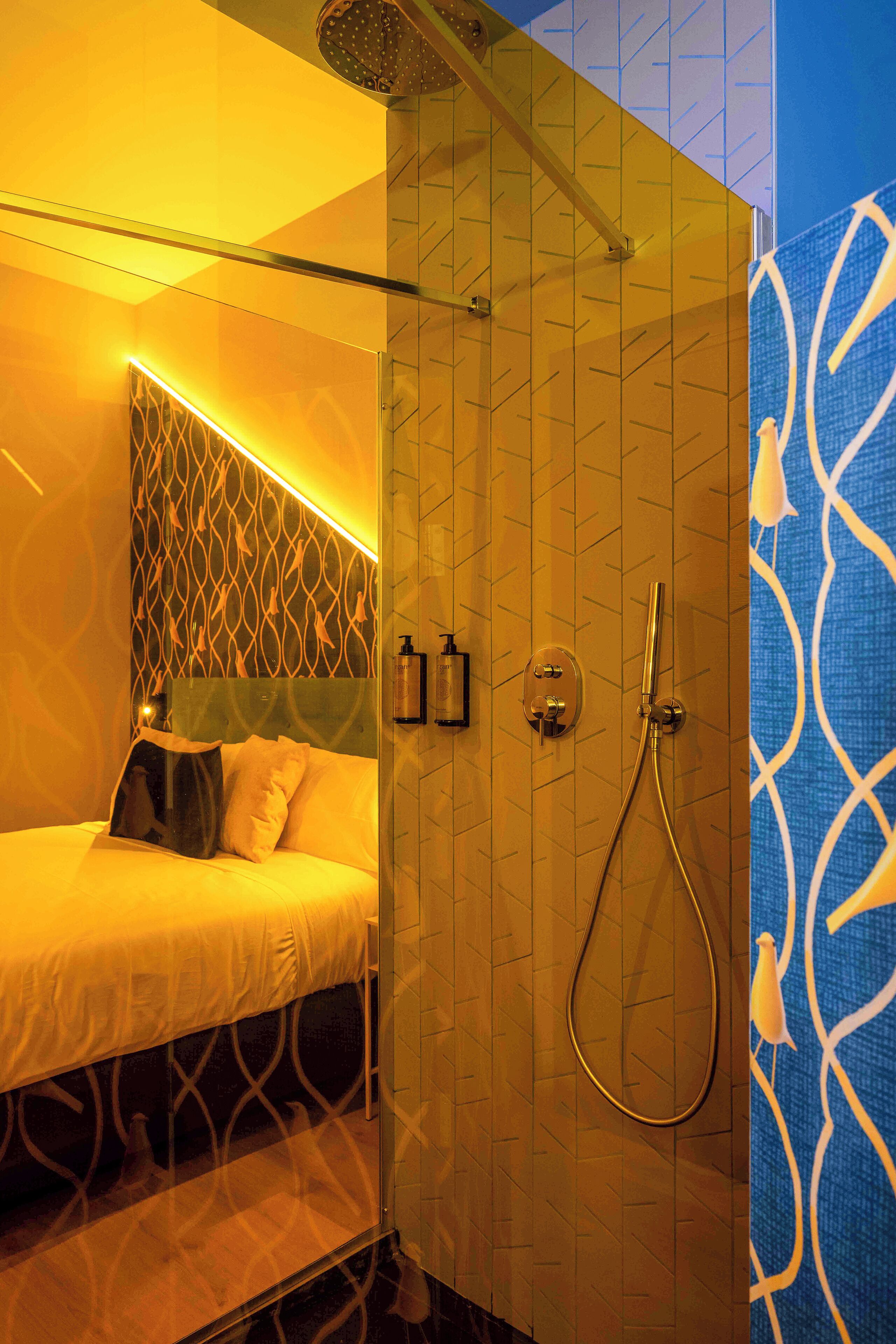 A modern hotel room with a bed, a shower, and a decorative wall.