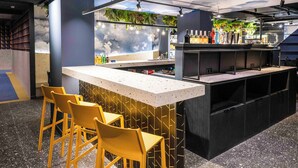 Un espace bar comprenant un comptoir, des tabourets de bar et une variété de bouteilles.