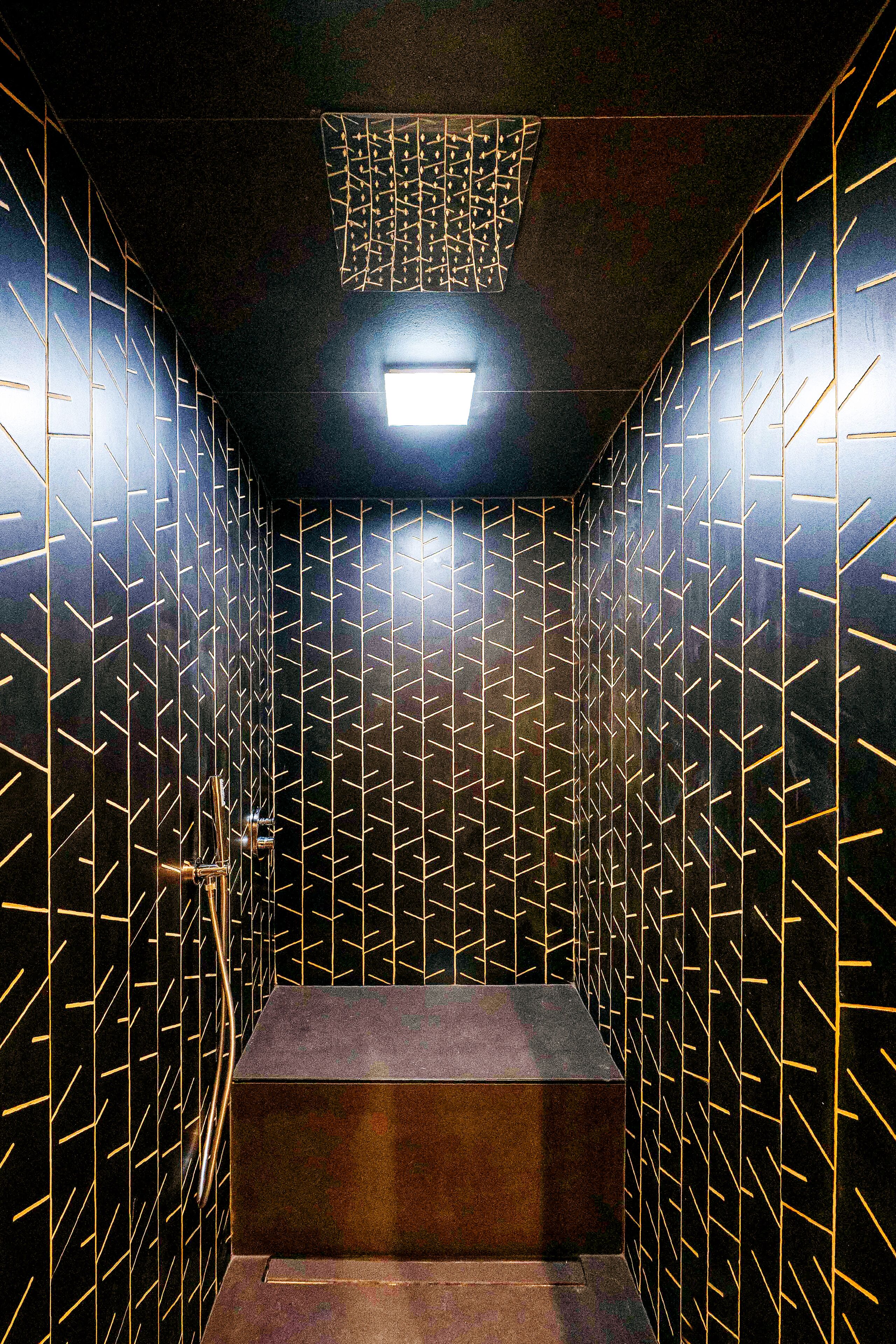 Un baño moderno con patrones geométricos en las paredes, un lavamanos central e iluminación en el techo.