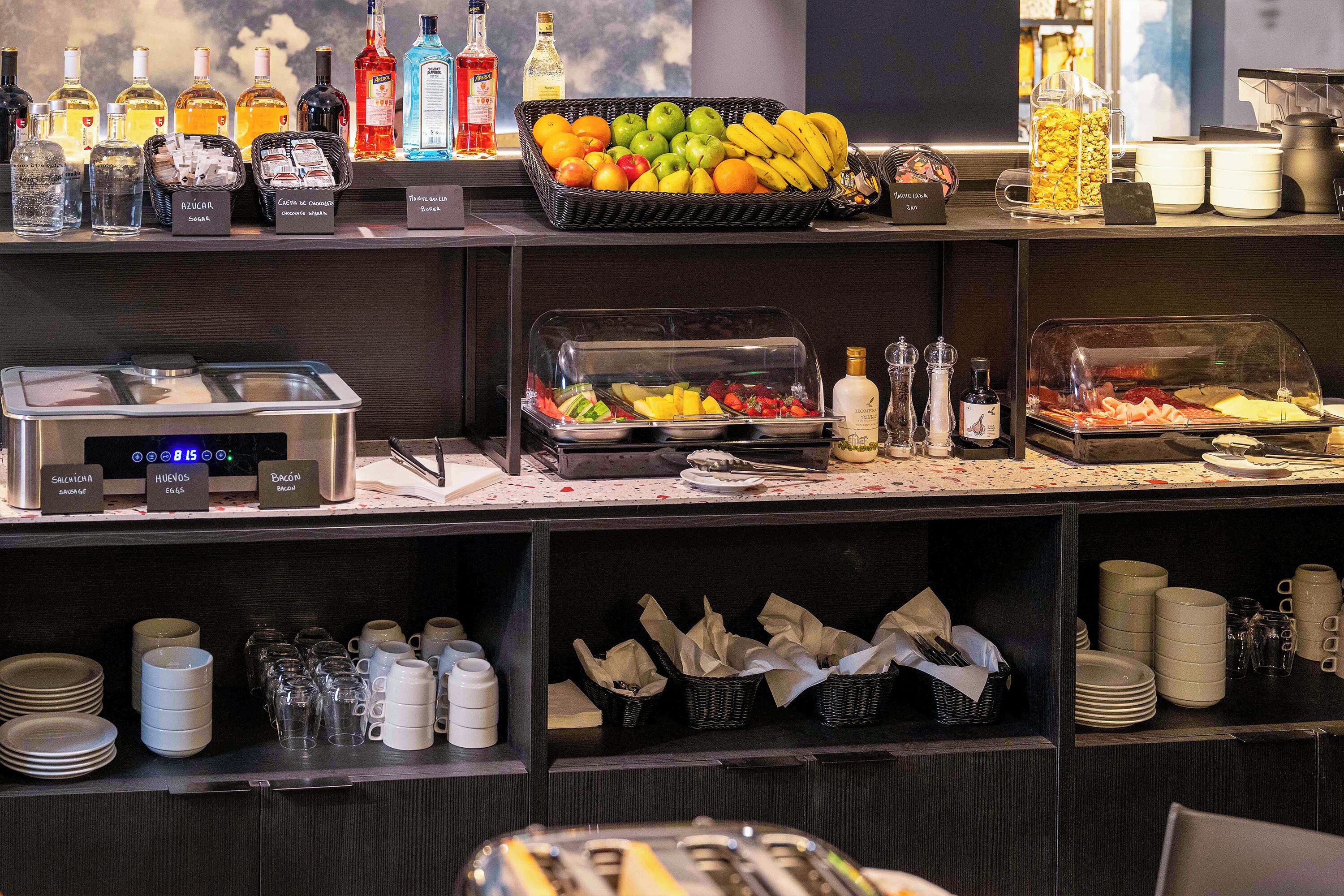 A buffet area with various food items, condiments, and beverages.