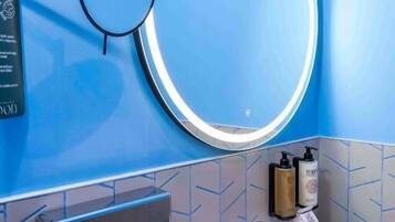 Un baño con un espejo grande, un lavamanos y un perchero para toallas.