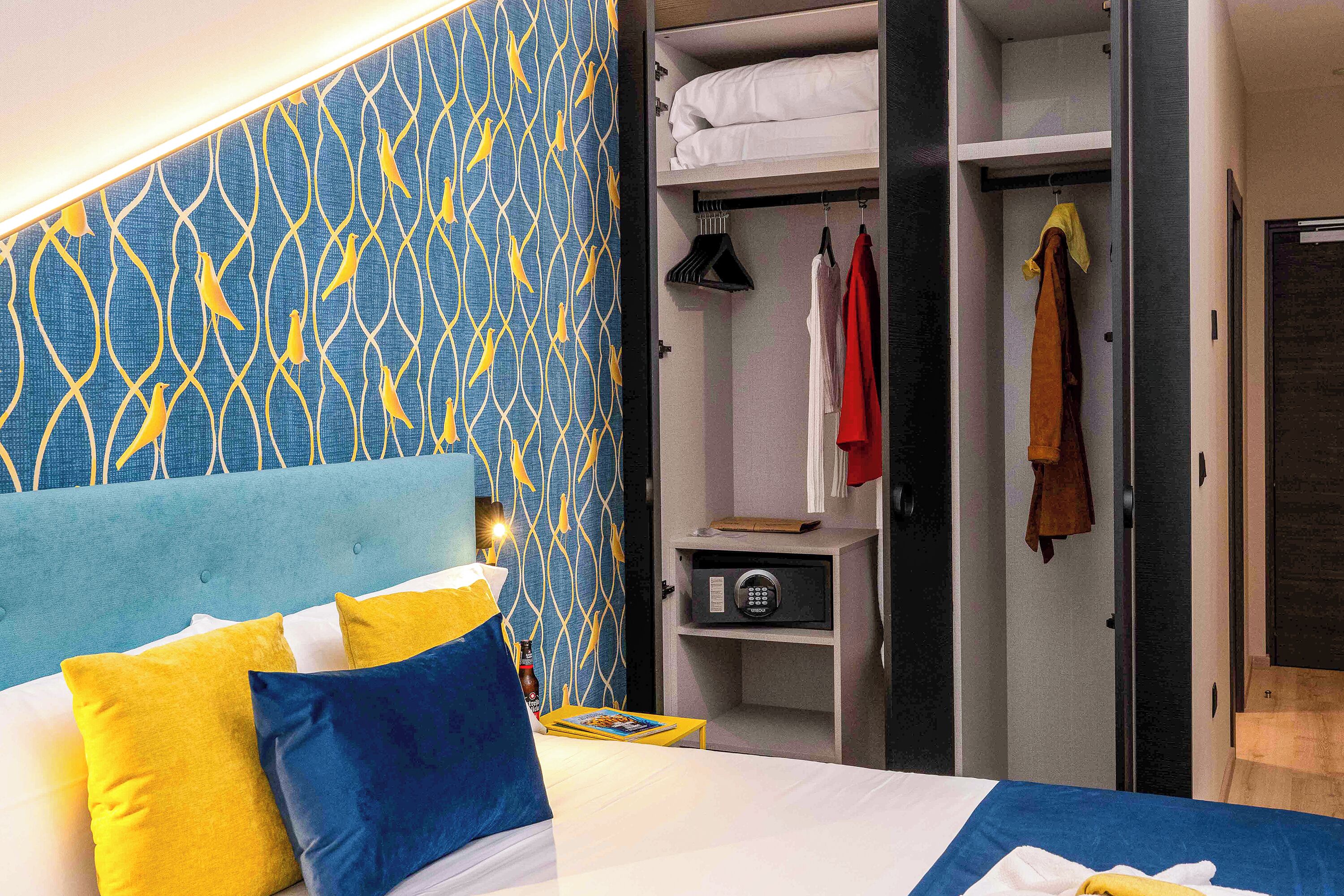 A hotel room with a bed, a wardrobe, and a nightstand.