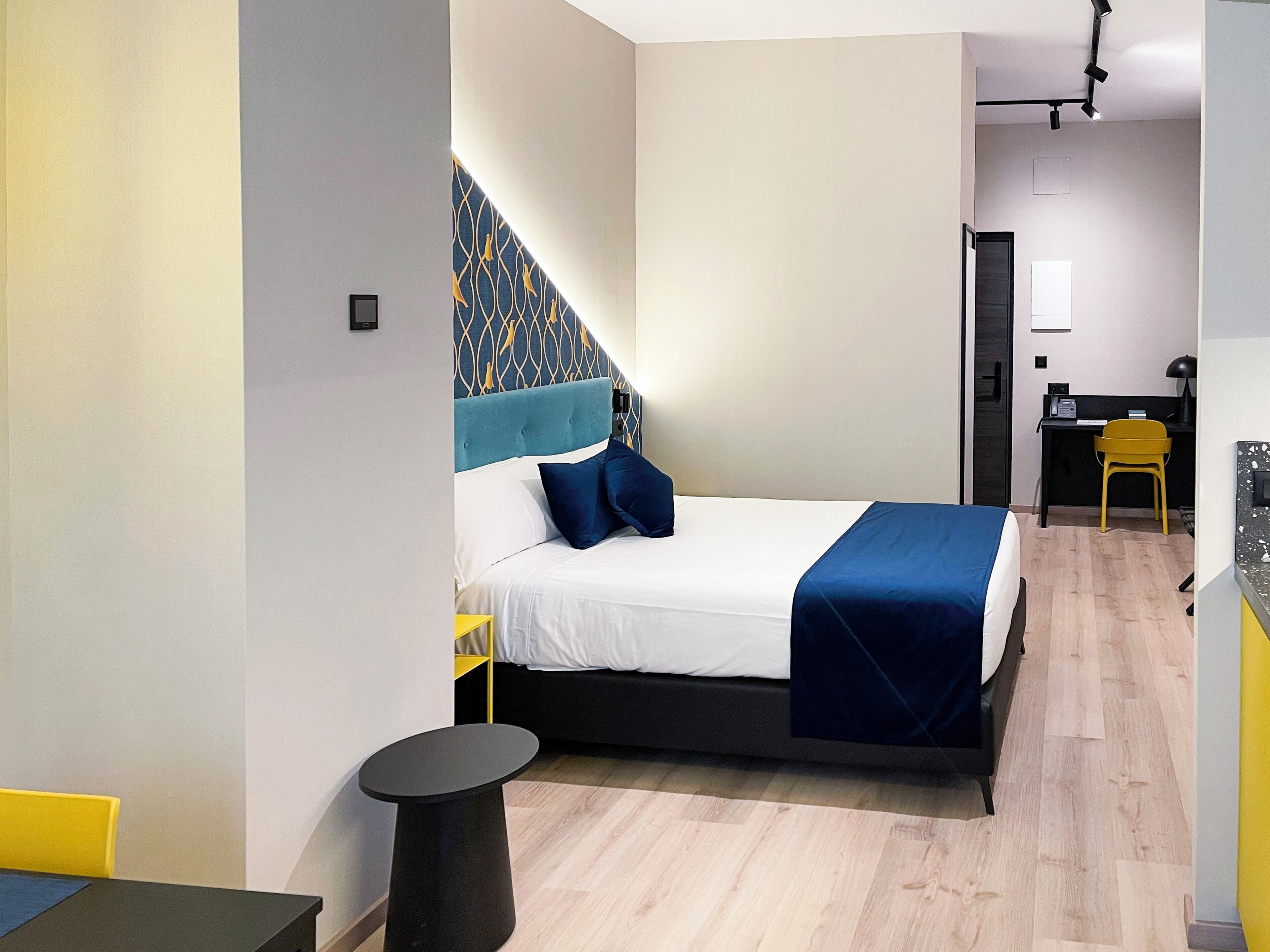 Une chambre d’hôtel moderne équipée d’un lit, d’une table de chevet et d’un bureau avec une chaise.