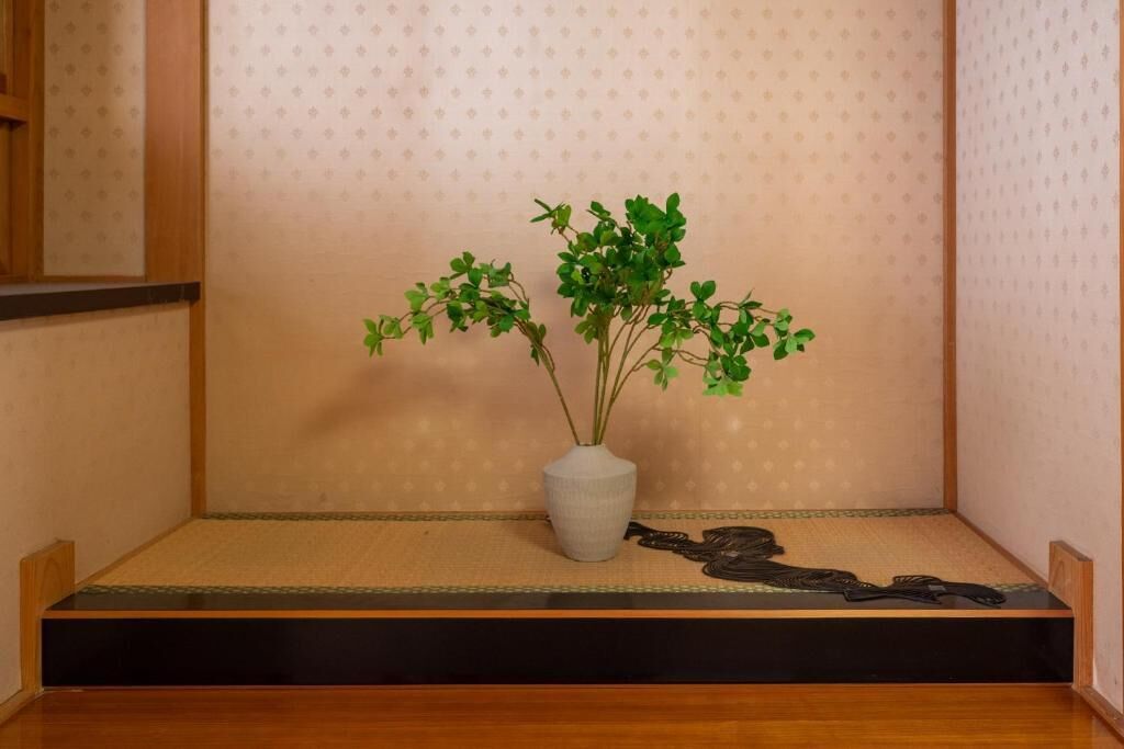 A tatami mat room with a small plant in a white vase and a decorative black object on the floor.