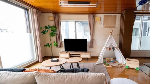 A modern living room with a sofa, a TV, a small table, and a tent-like structure. - Nakamachi House (Biei)