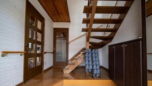 A staircase with wooden beams and a glass door at the top. - Nakamachi House (Biei)
