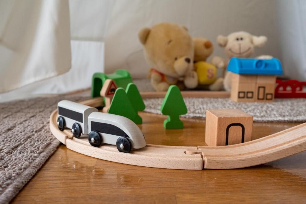 A wooden toy train set with a track, a bear, and a house.