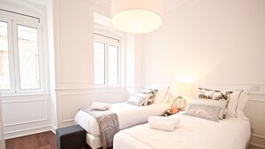 Ein Hotelzimmer mit zwei Betten, einer kleinen Bank und einem Fenster.