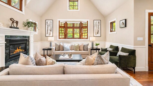 A spacious living room with a fireplace, a large sofa, a coffee table, and a view of the outdoors through a window. - Updated Spacious Home w AC & Hot Tub Walk to Town! (Aspen)