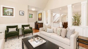 A living room with a sofa, two armchairs, a coffee table, and a staircase leading to another level. - Updated Spacious Home w AC & Hot Tub Walk to Town! (Aspen)