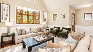 A spacious living room with a high ceiling, large windows, and a cozy seating area. - Updated Spacious Home w AC & Hot Tub Walk to Town! (Aspen)