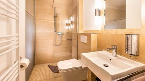 Ein modernes Badezimmer mit einer begehbaren Glasdusche, einem weißen Waschbecken und einer Toilette.