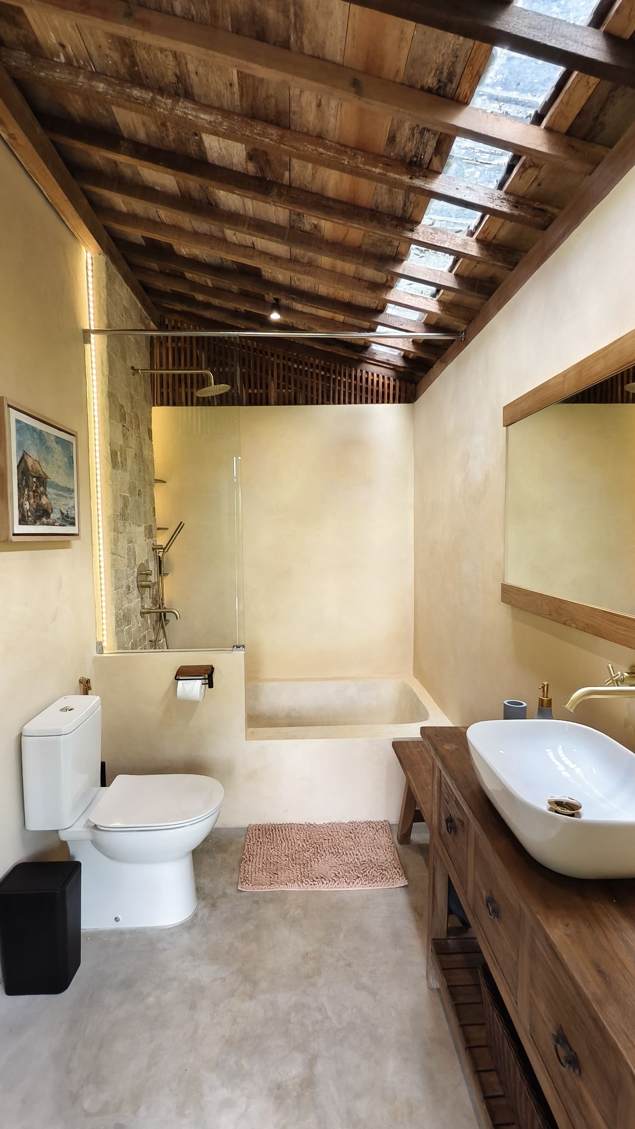 A bathroom with a wooden ceiling, a bathtub, a toilet, a sink, and a mirror.
