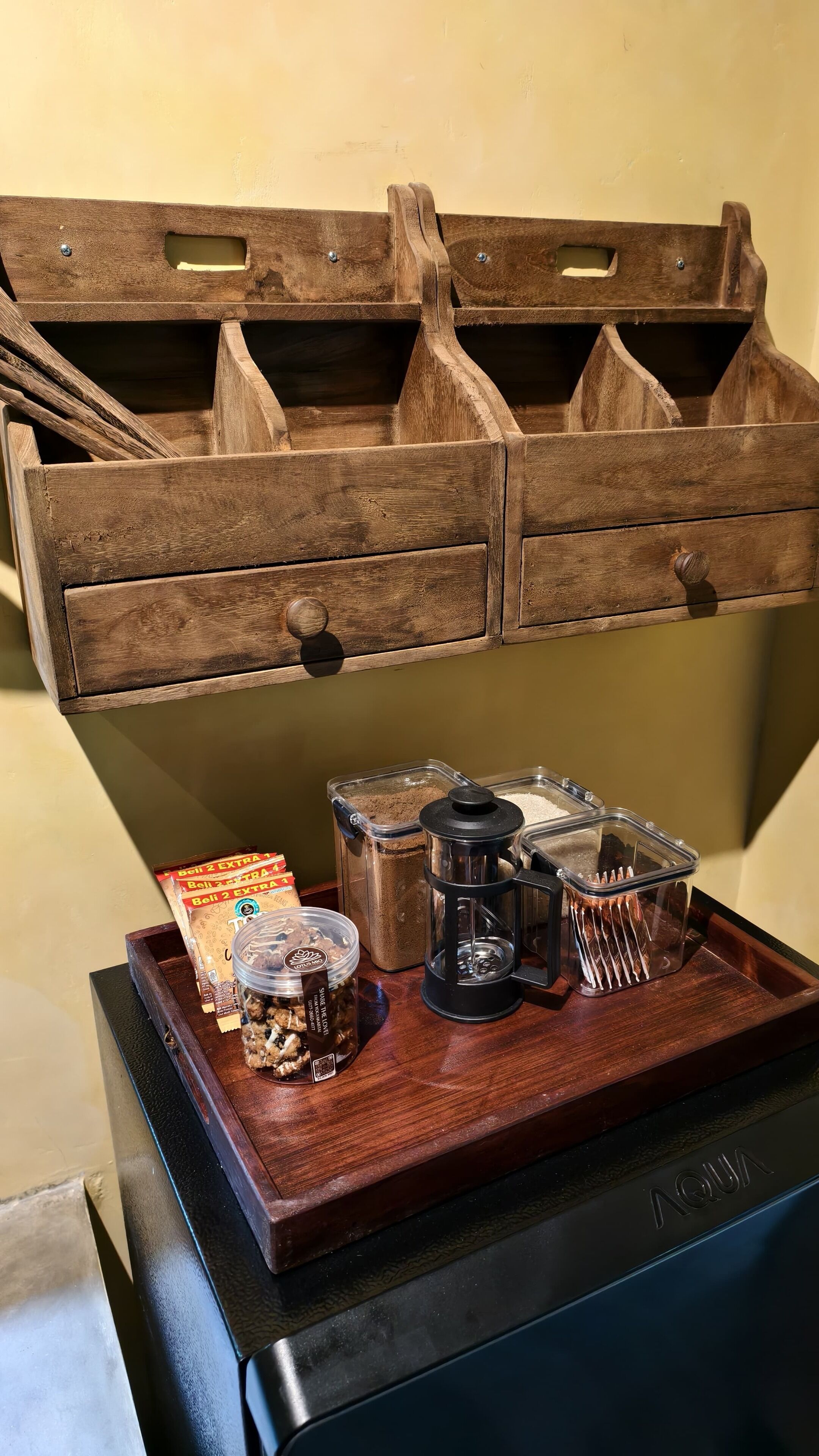 A wooden chest with compartments containing a coffee grinder, a jar of biscotti, and a packet of biscotti.