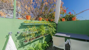 Un jardin sur le toit, avec des plantes en pot et une table entourée de chaises.