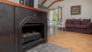 Un salon avec une cheminée, un canapé marron et une table en verre avec des chaises.