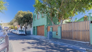 Une rue bordée de voitures garées et un immeuble à la façade verte.
