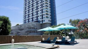 A hotel with a pool area, lounge chairs, and umbrellas.