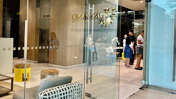 A modern interior with a glass partition, wooden flooring, and a seating area with woven chairs.