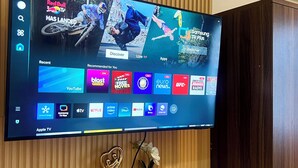 A flat-screen TV mounted on a wooden wall with a wooden shelf below.