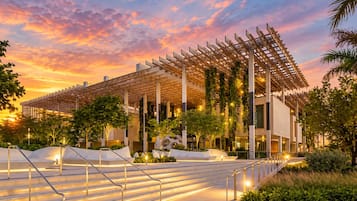 A modern building with a wooden pergola, outdoor stairs, and greenery.