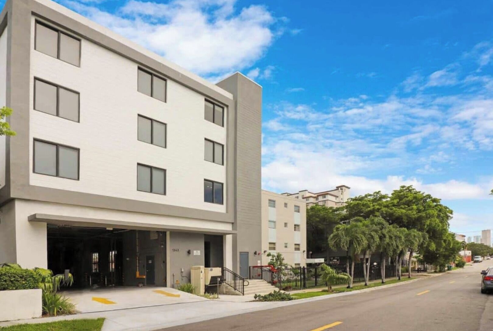 Un edificio moderno de varios pisos con fachada plana, ventanas amplias y vestíbulo cubierto.