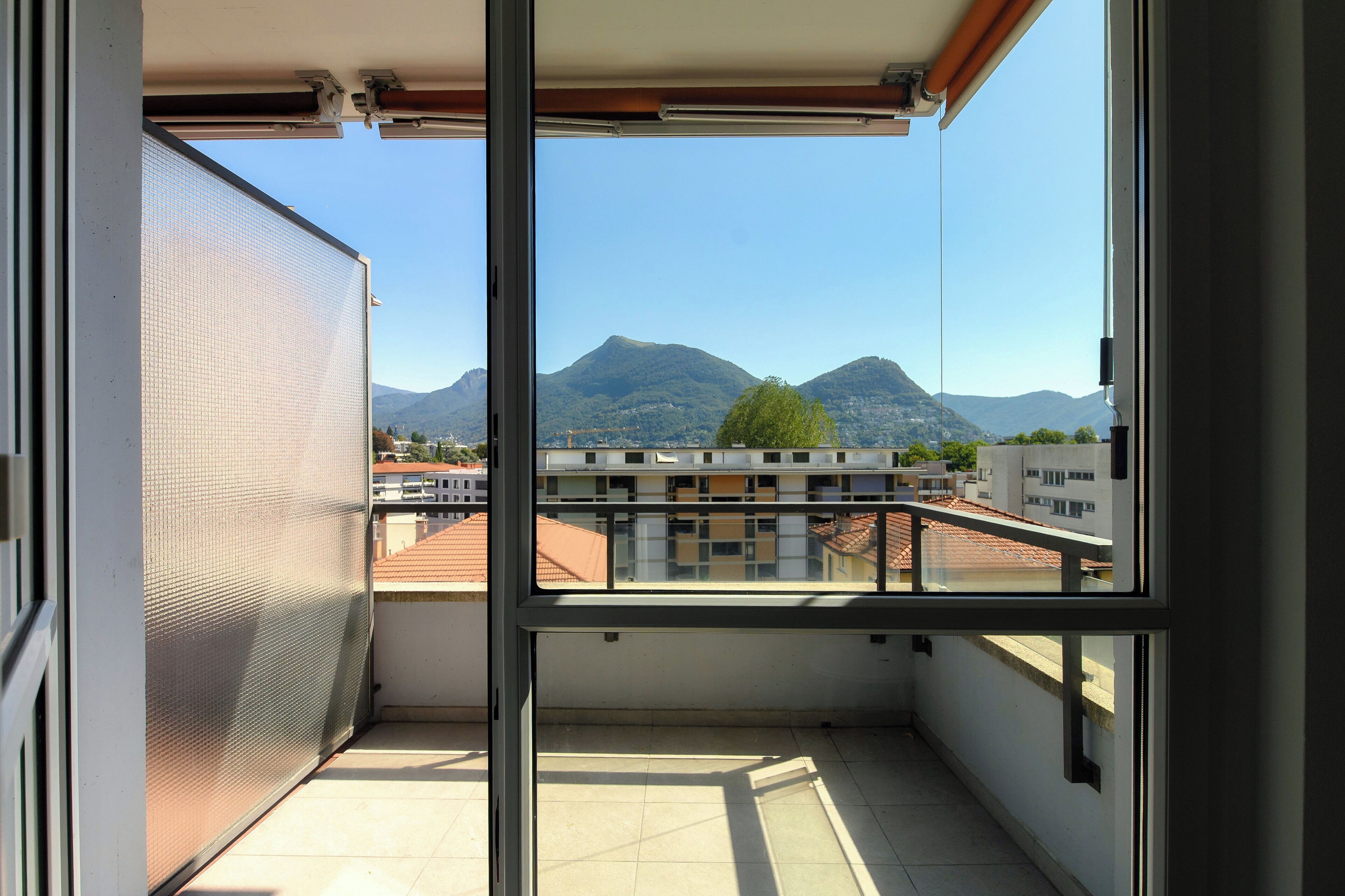 A balcony with a view of mountains and buildings.