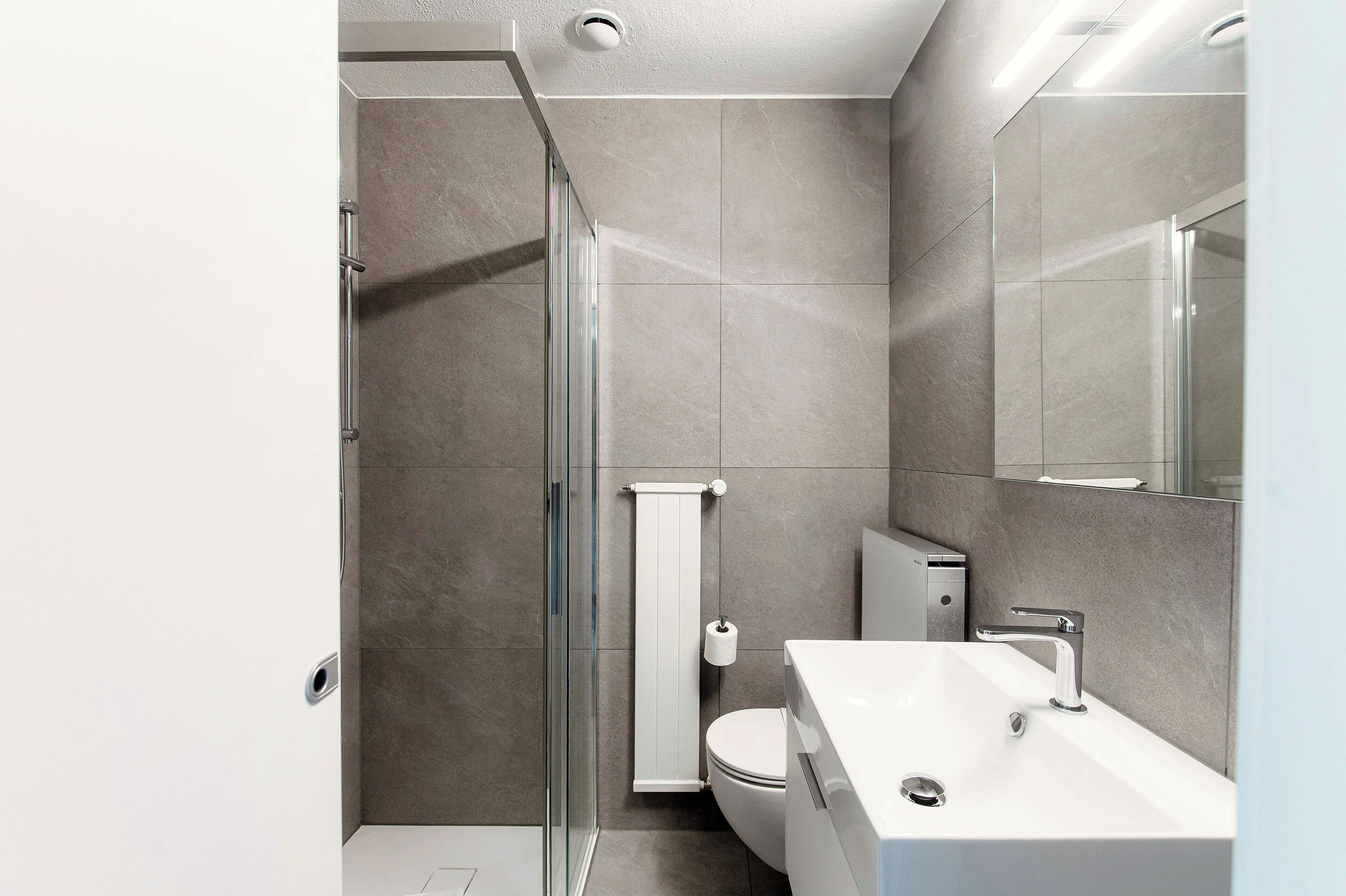 A modern bathroom with a glass shower enclosure, a white toilet, and a sink with a chrome faucet.